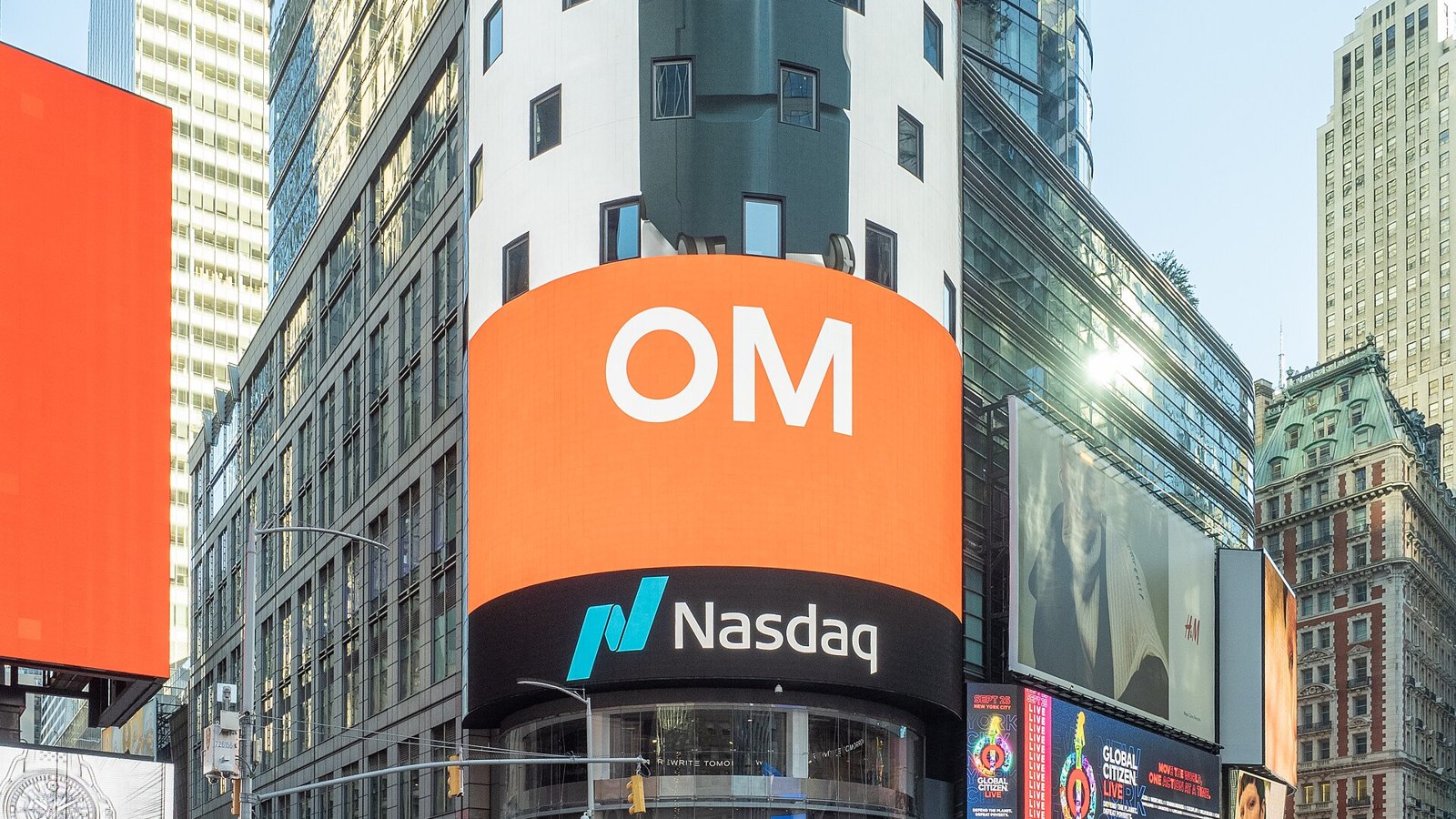 La tour cylindrique du Nasdaq MarketSite à Times Square, avec un grand écran orange et le logo Nasdaq