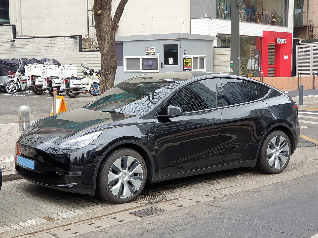 Un Tesla Model Y noir garé le long d'un trottoir dans une rue commerçante de Séoul